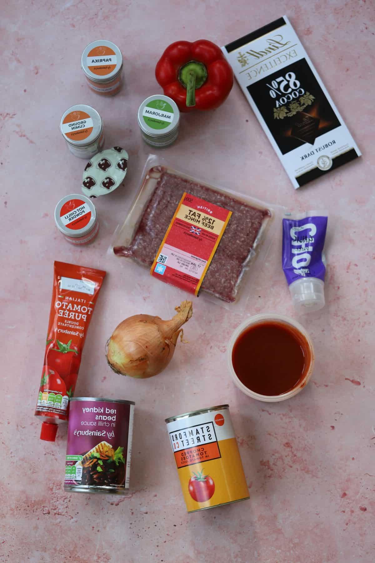 Chilli Con Carne Senza Glutine 4 Gli ingredienti per un chilli con carne su uno sfondo rosa.