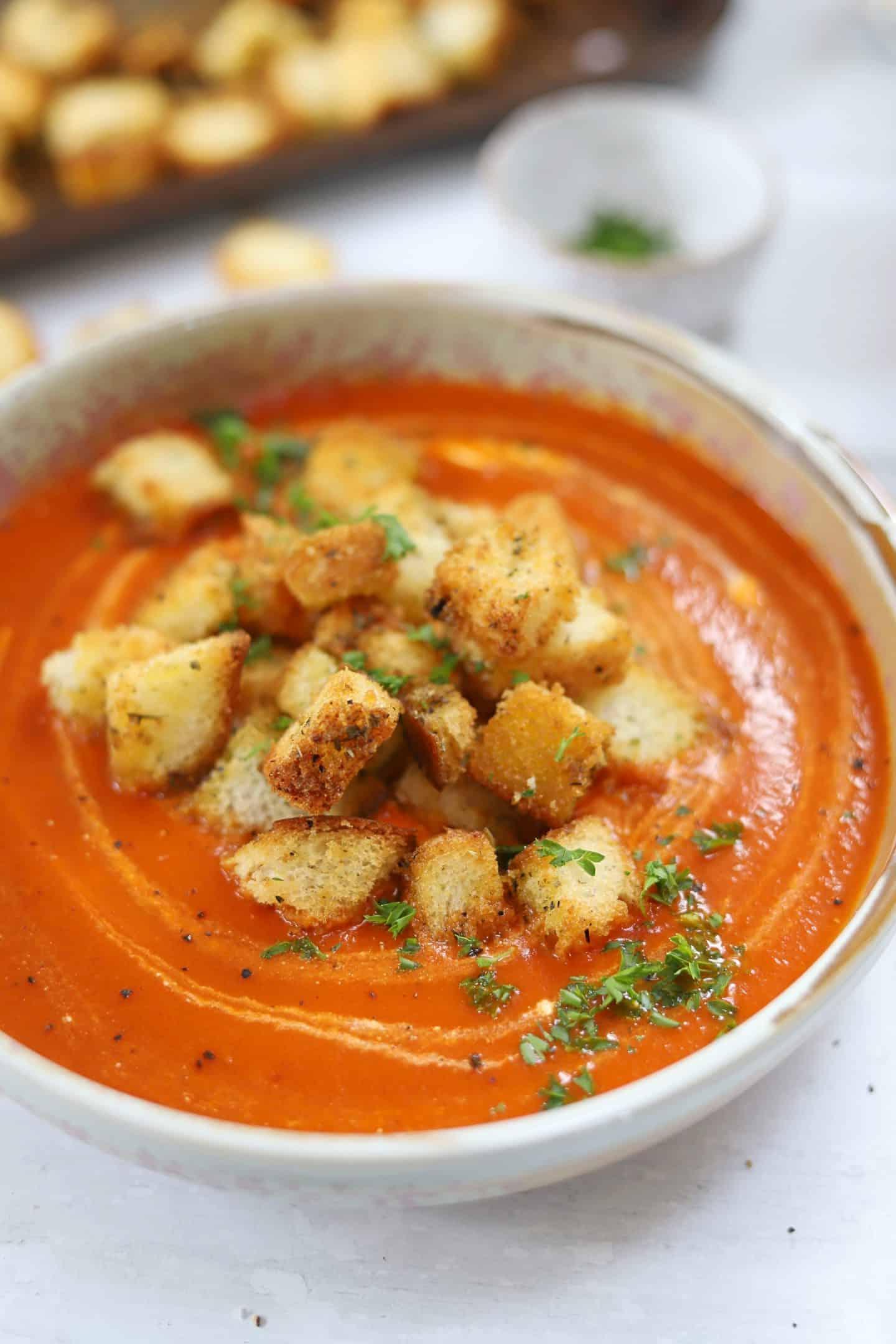 Zuppa di pomodoro senza glutine 4 Una ciotola di zuppa di pomodoro senza glutine con harissa guarnita con crostini senza glutine e un tocco di panna acida.