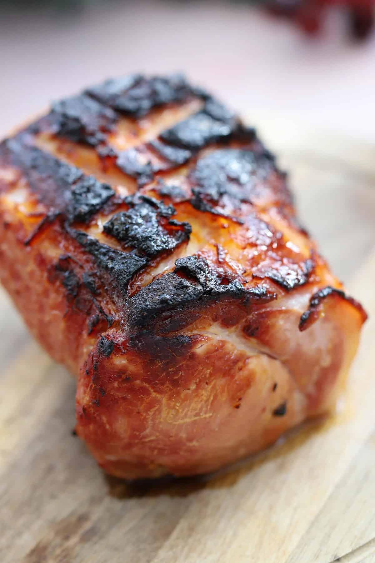 Un prosciutto cotto in slow cooker su un tagliere con glassa di marmellata.