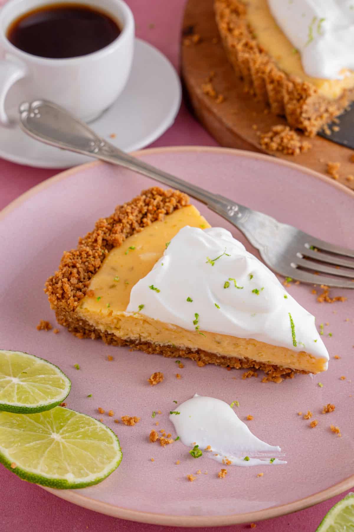 Torta al Lime Senza Glutine 4 Una fetta di Torta Key Lime senza glutine su un piatto rosa.