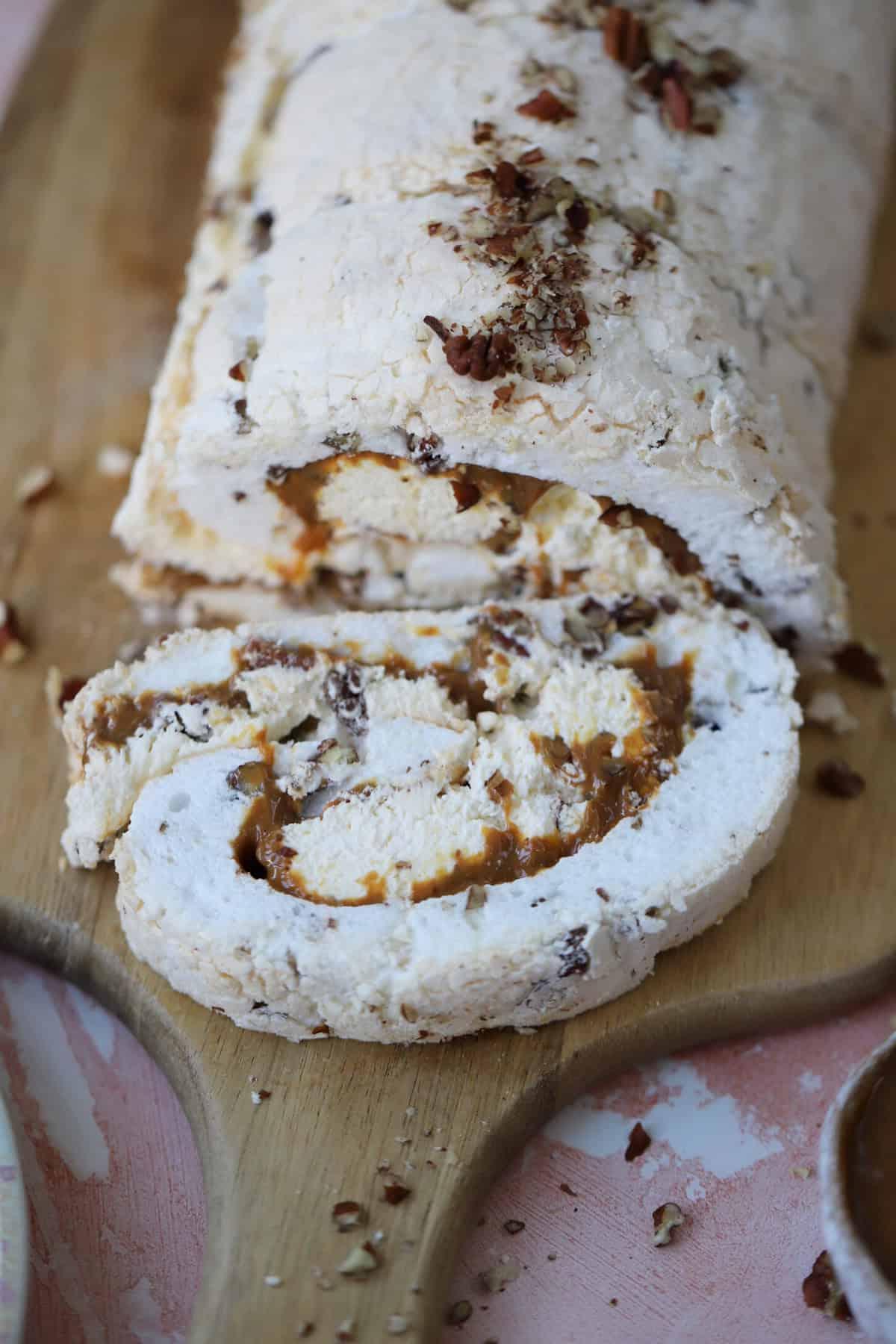 25+ Dolci Natalizi Senza Glutine 6 A toffee and pecan meringue roulade on a wooden board.