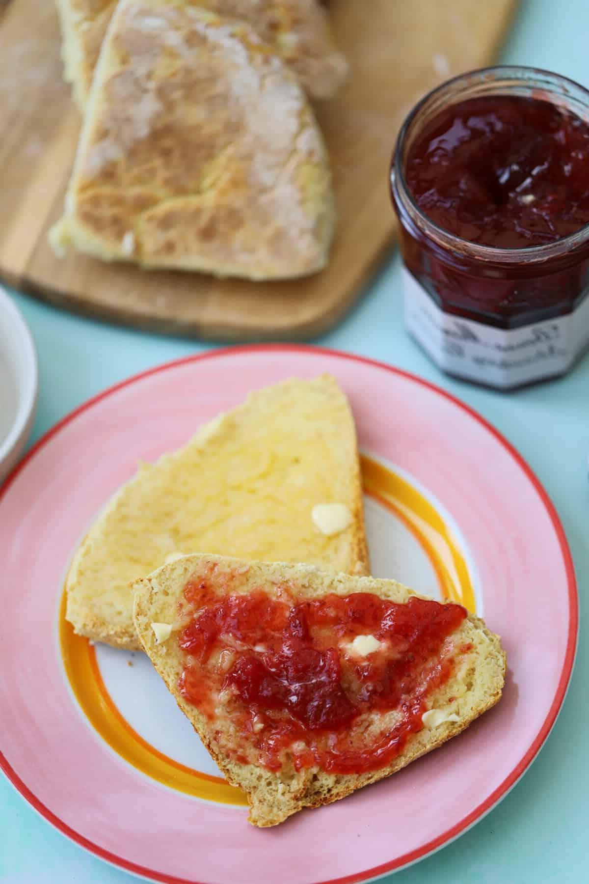 Un farl di soda irlandese tagliato a metà con burro e marmellata sopra.