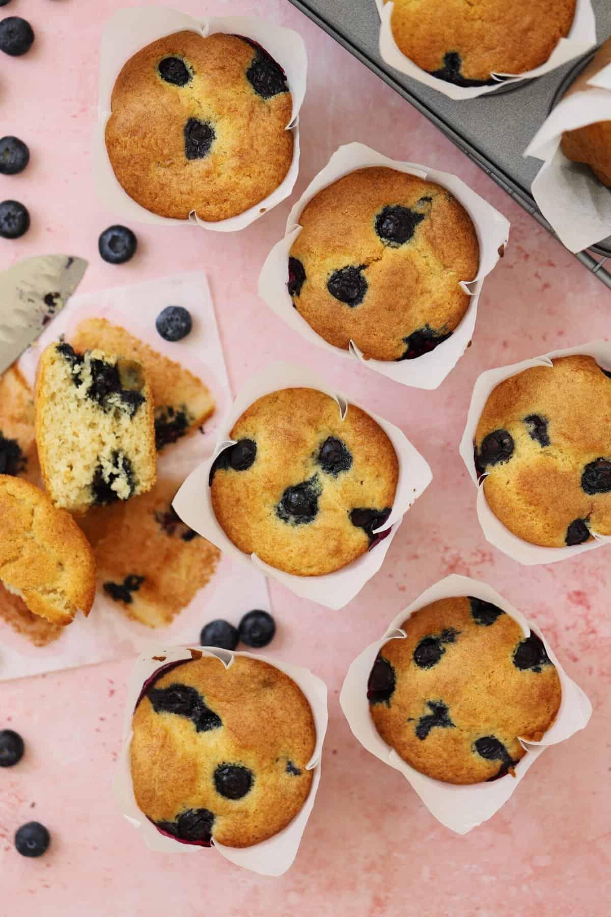 Muffins ai Mirtilli Senza Glutine 8 Muffin ai mirtilli senza glutine su uno sfondo rosa.