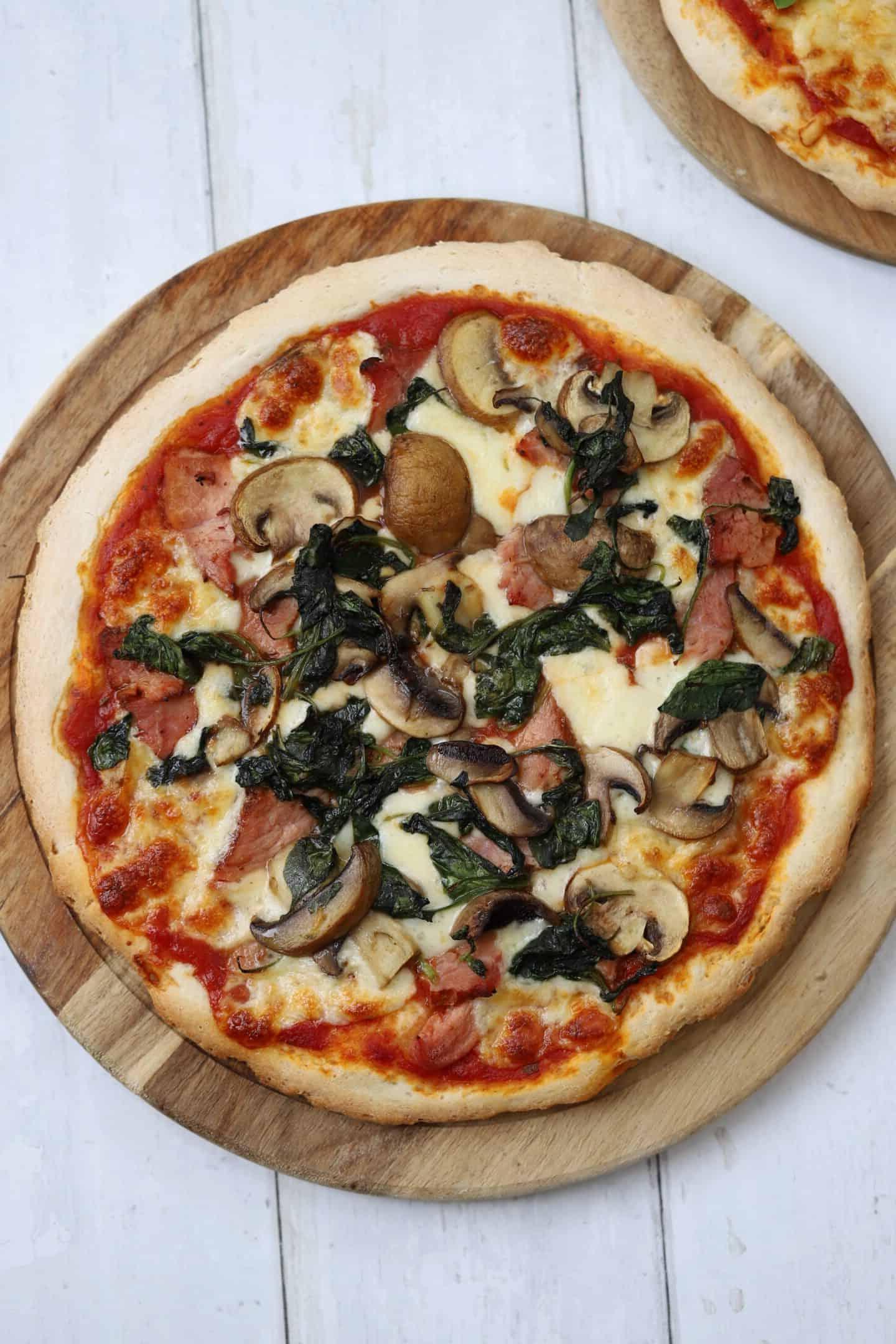 Caputo Impasto per Pizza Senza Glutine 9 Una pizza senza glutine con prosciutto e funghi su un tagliere di legno, pronta per essere gustata.
