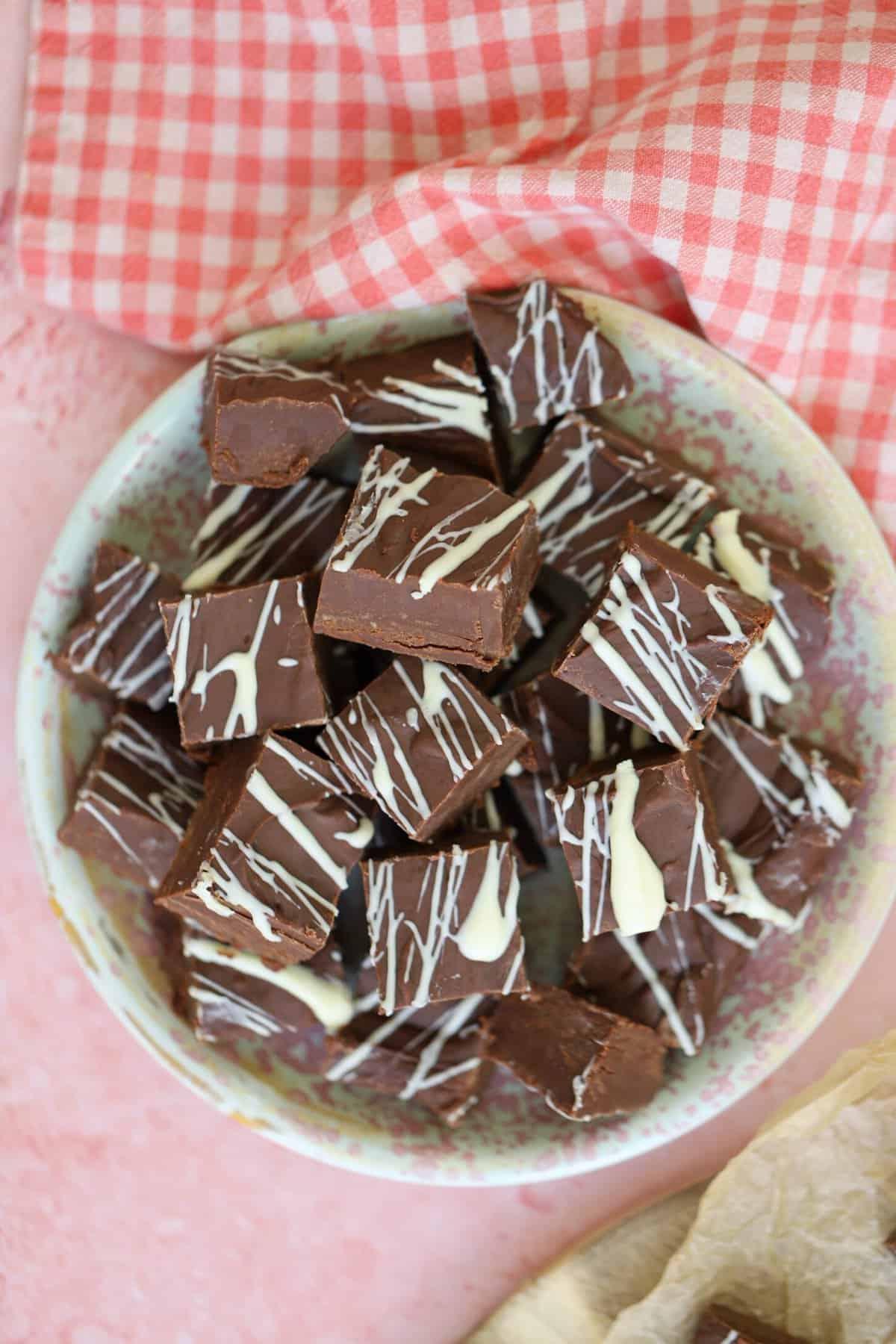 Fudge al Cioccolato in Slow Cooker 9 Vista dall'alto di un piatto di fudge fatto nella slow cooker su un piano di lavoro rosa.
