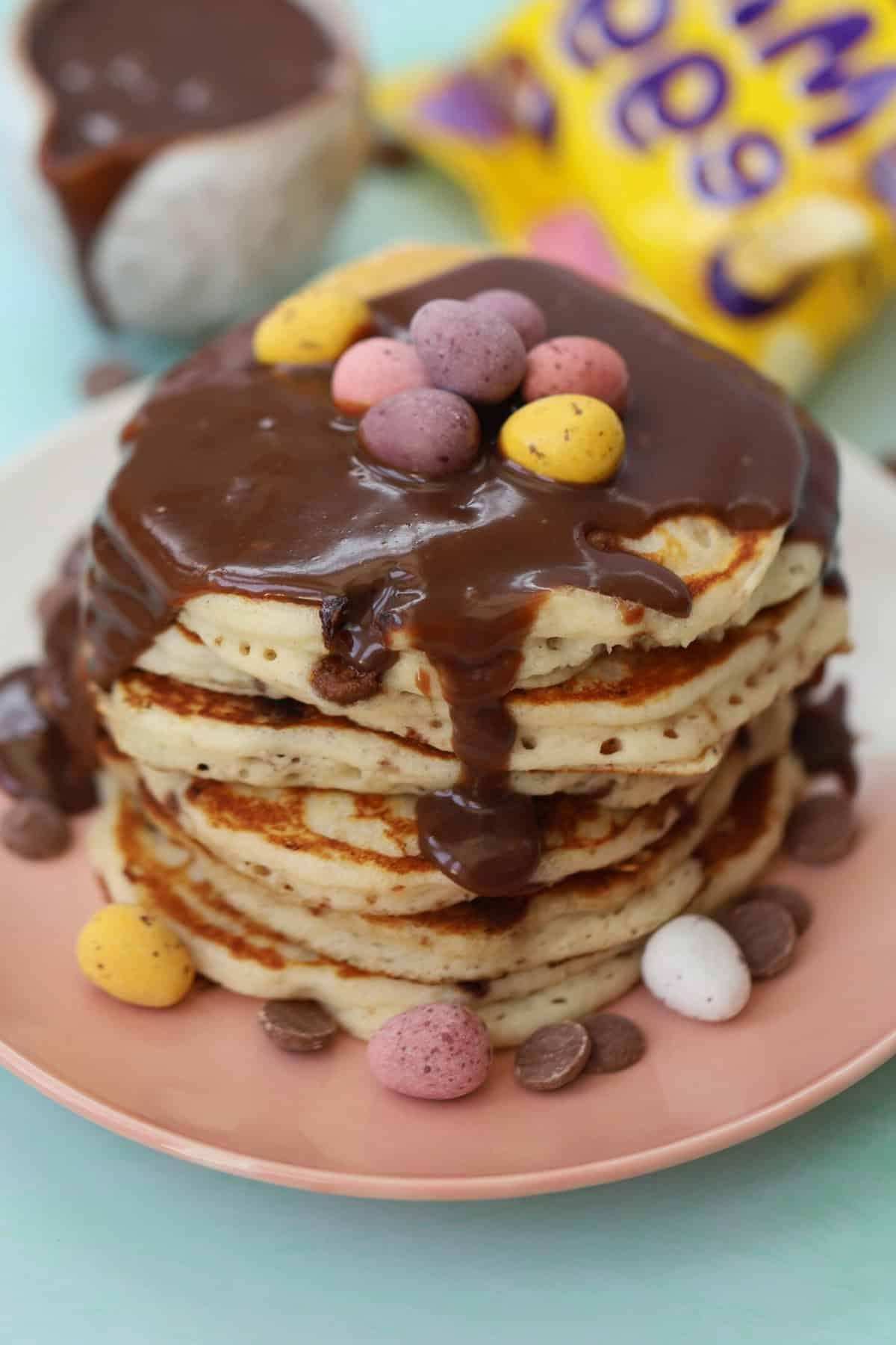 Mini Pancakes all'Uovo Senza Glutine 2 Un'alta pila di pancakes con mini uova di cioccolato e glassa al cioccolato.