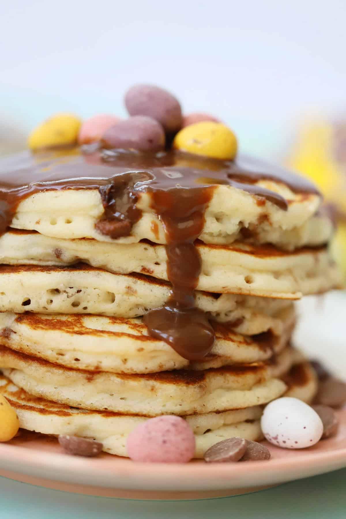 Mini Pancakes all'Uovo Senza Glutine 3 Una pila di pancakes con mini uova di cioccolato e glassa al cioccolato sopra.