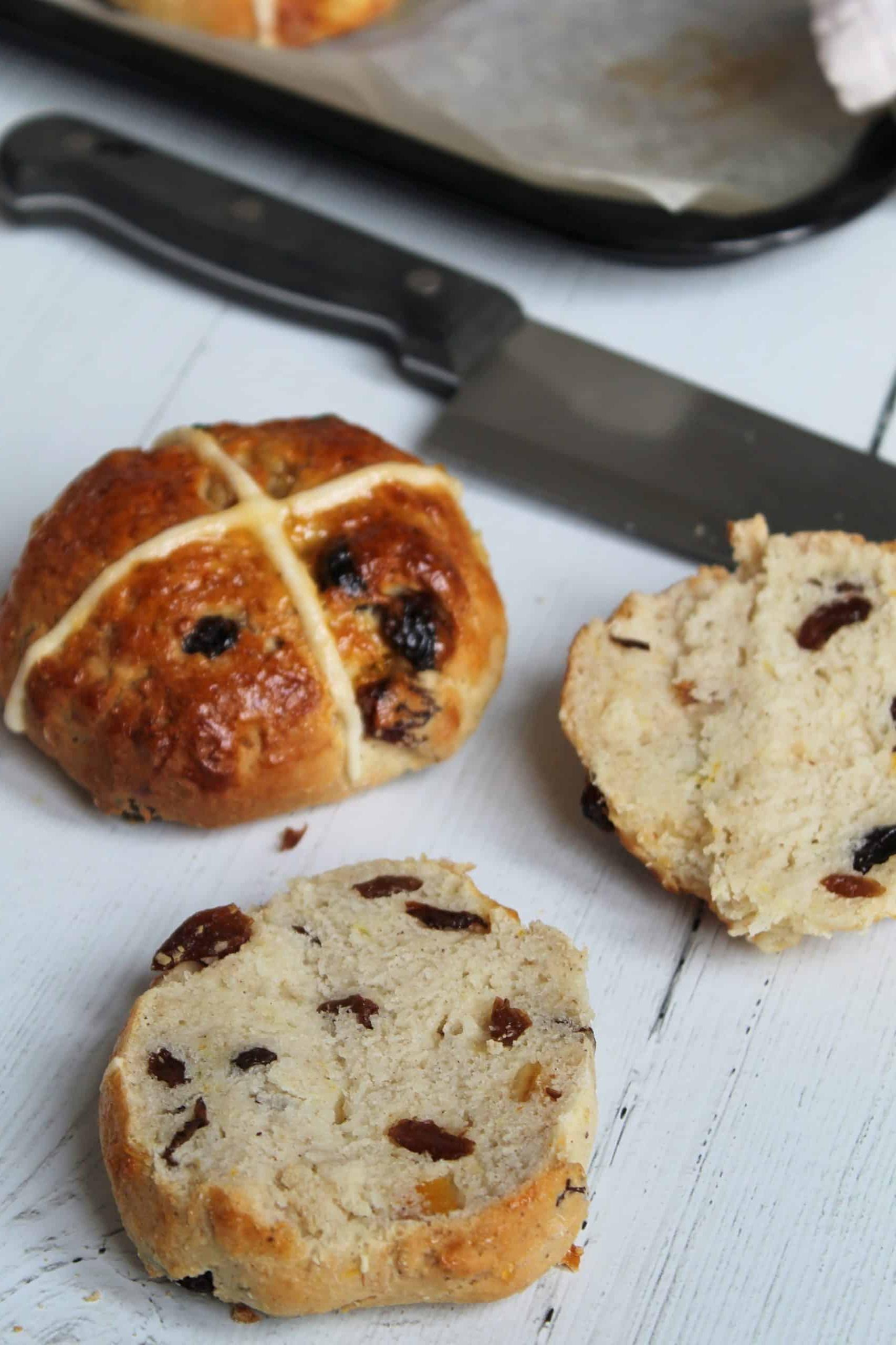 Un Hot Cross Bun senza glutine tagliato a metà, che mostra la sua consistenza morbida e i frutti all'interno.