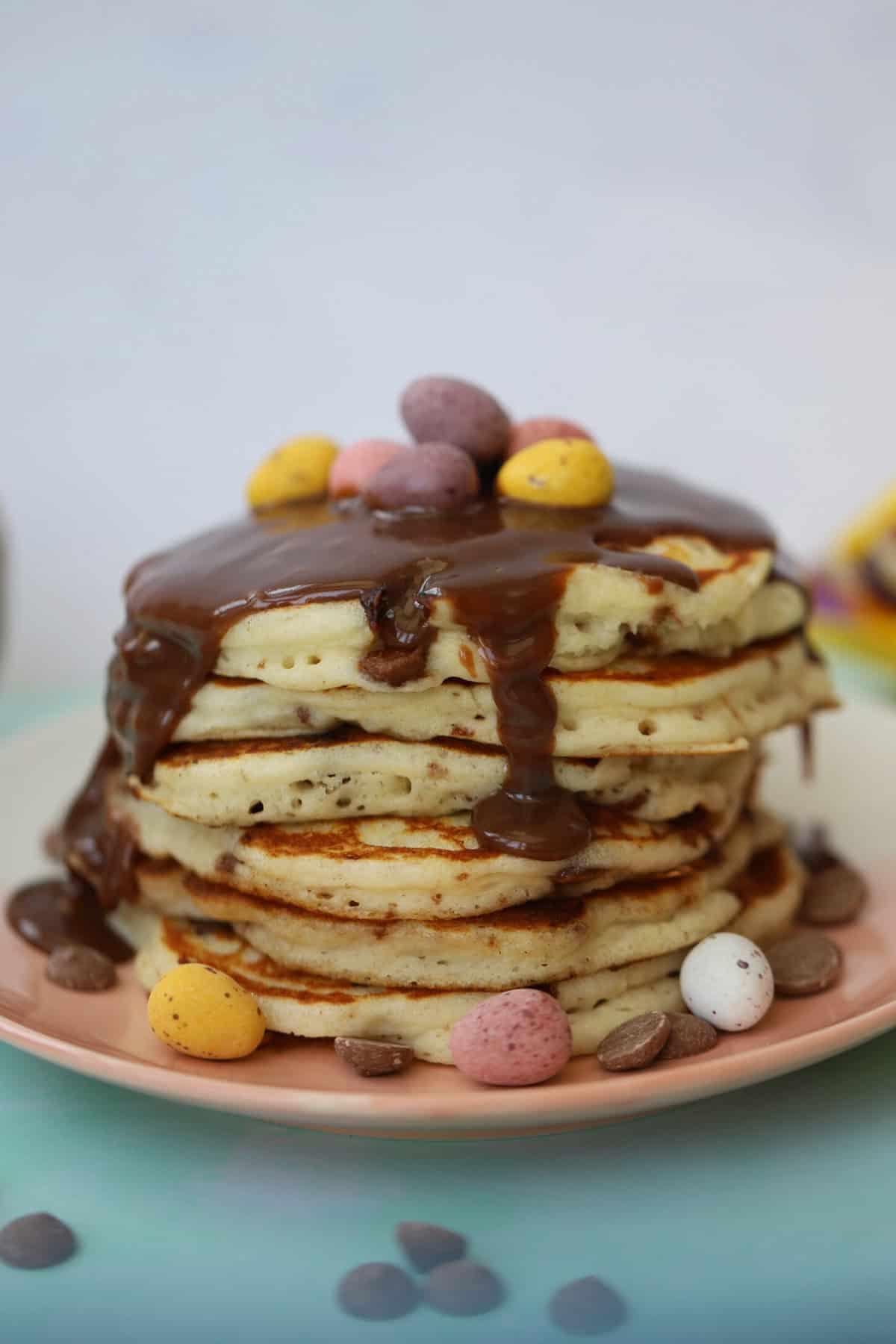 Mini Pancakes all'Uovo Senza Glutine 10 Una pila di pancakes con mini uova di cioccolato e glassa al cioccolato sopra.