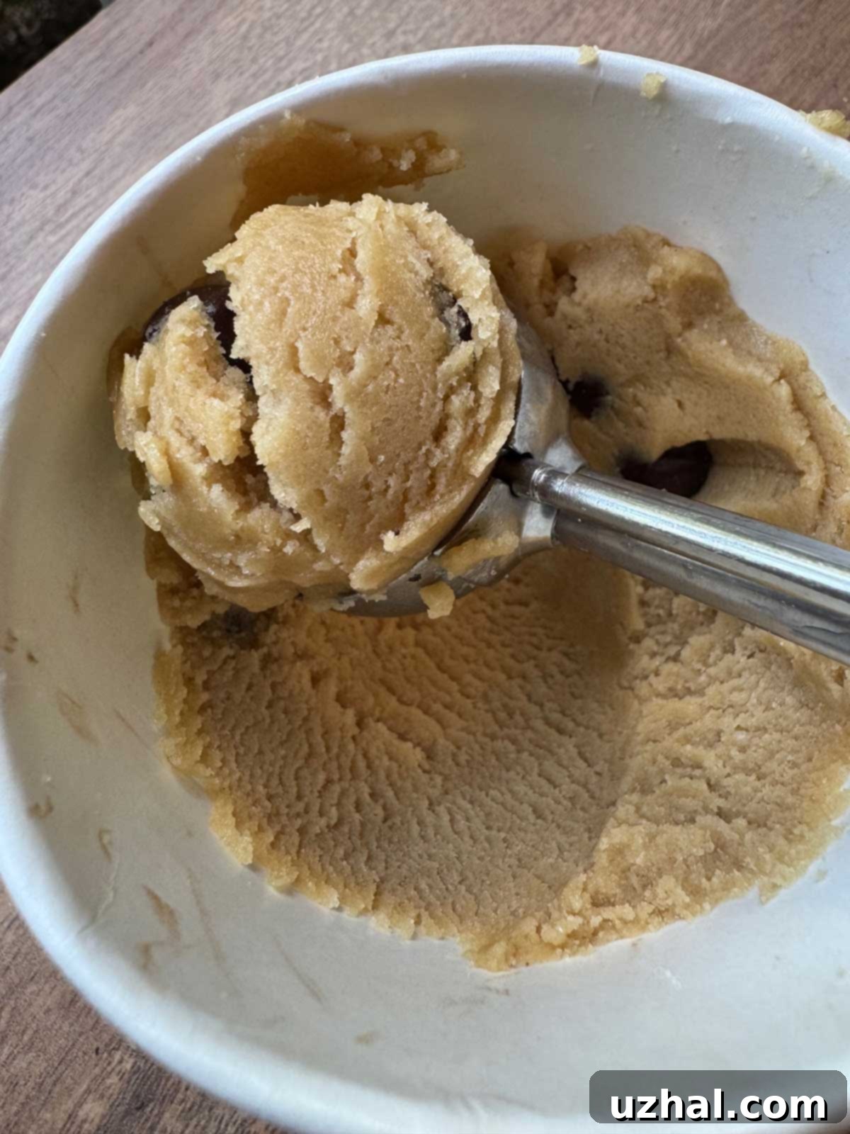Scooped dairy free chocolate chip cookie dough portioned into a small white ice cream carton, ready for gifting or storage.