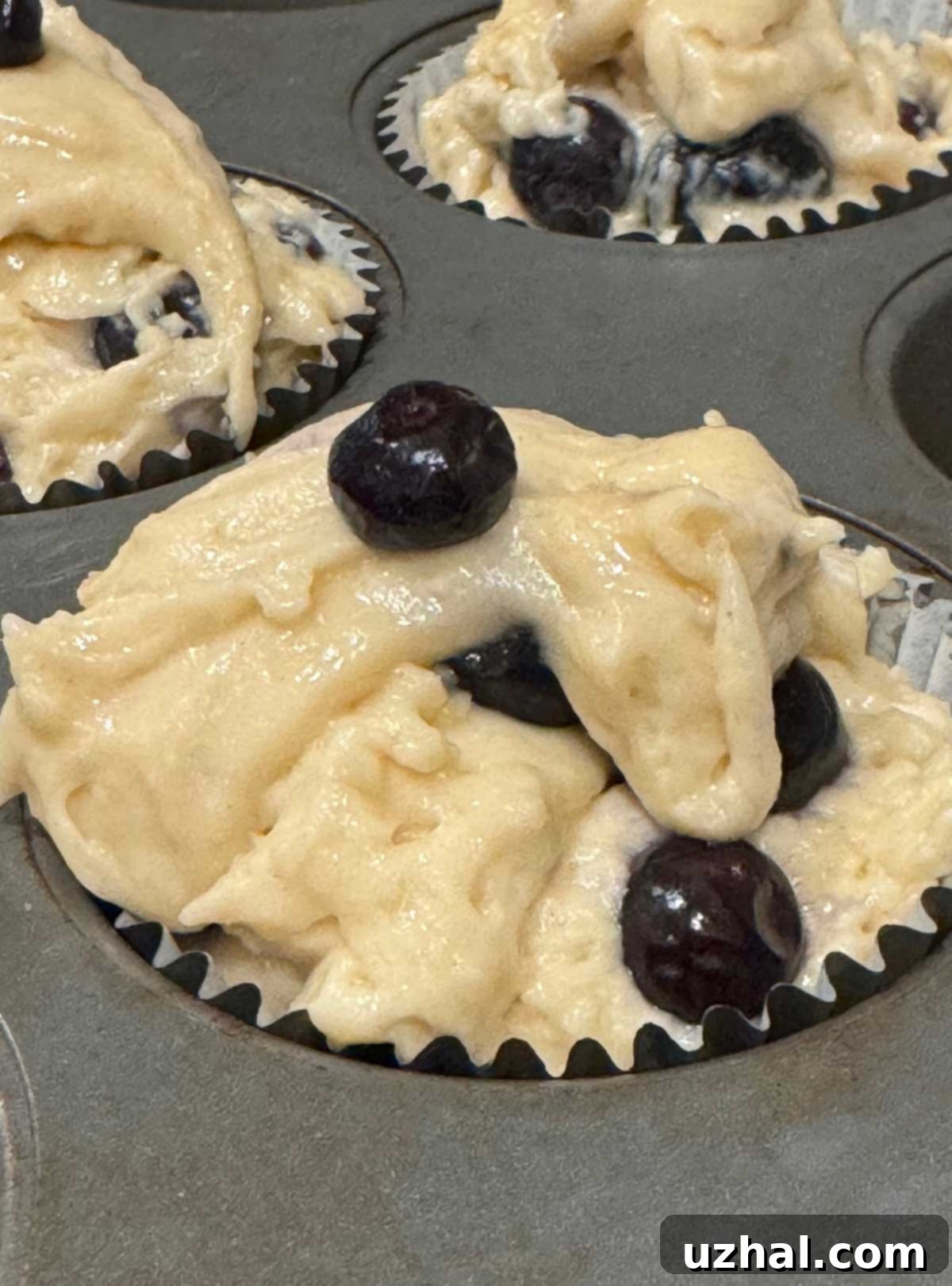 Muffin batter generously piled high in a muffin cup, ready for baking Greek Yogurt Blueberry Muffins.