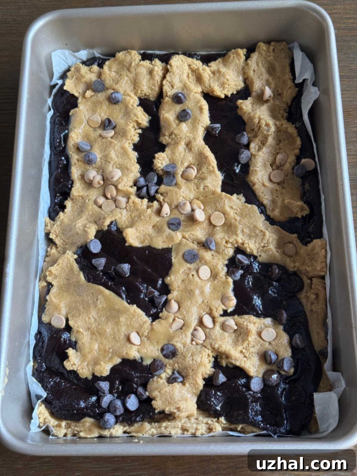 Decadent Peanut Butter Brookies 4 An overhead view of unbaked Peanut Butter Brookies in a baking pan, demonstrating the artistic layering technique of dollops of golden peanut butter cookie dough and luscious brownie batter before baking.