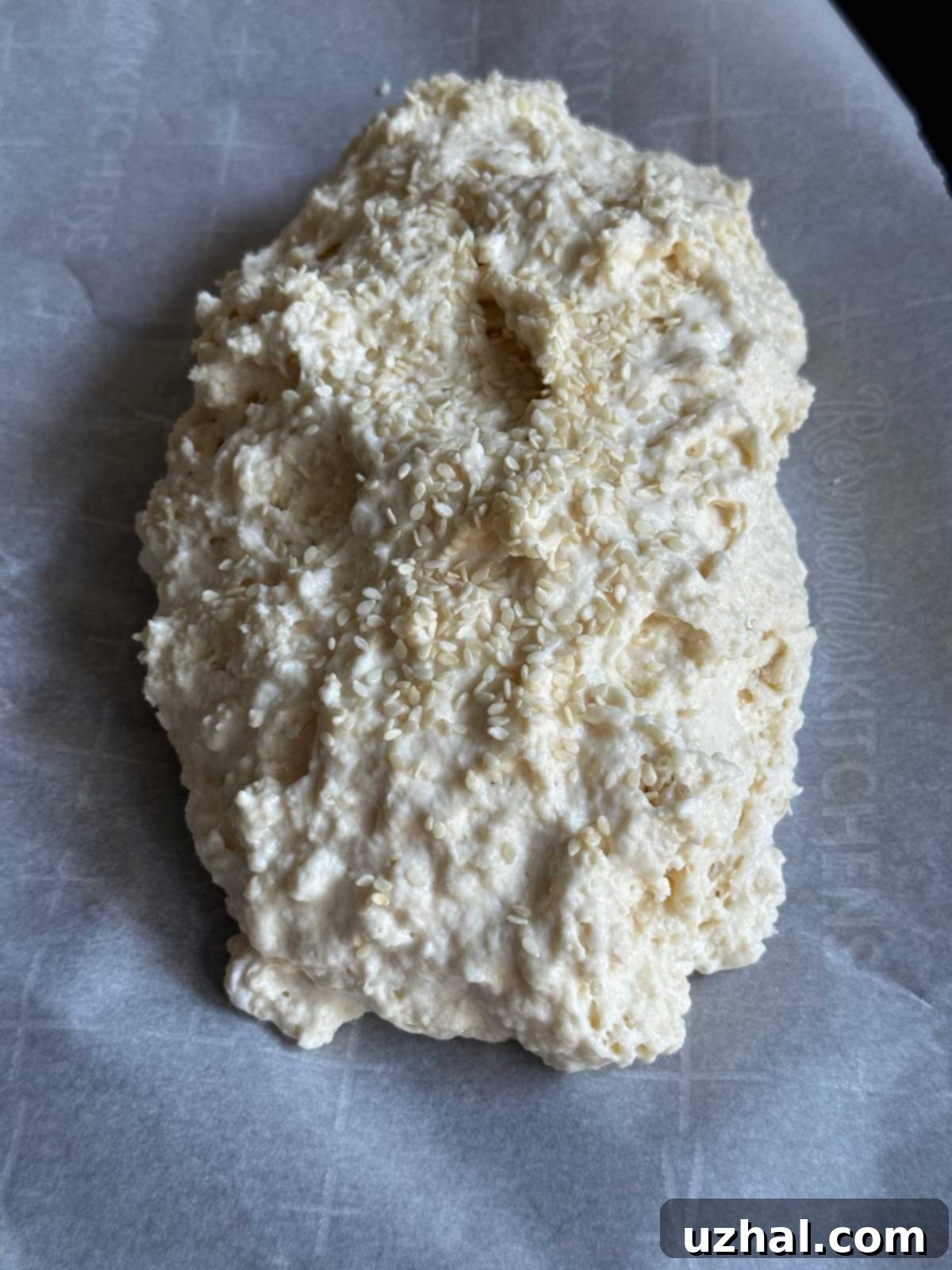 An unbaked loaf of no-yeast bread on a piece of parchment paper.