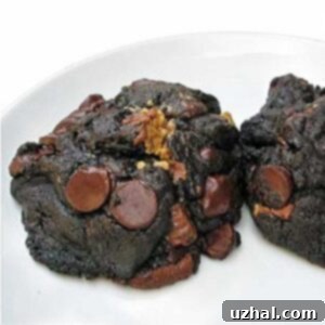Freshly baked giant dark chocolate cookies with peanut butter chips cooling on a rack