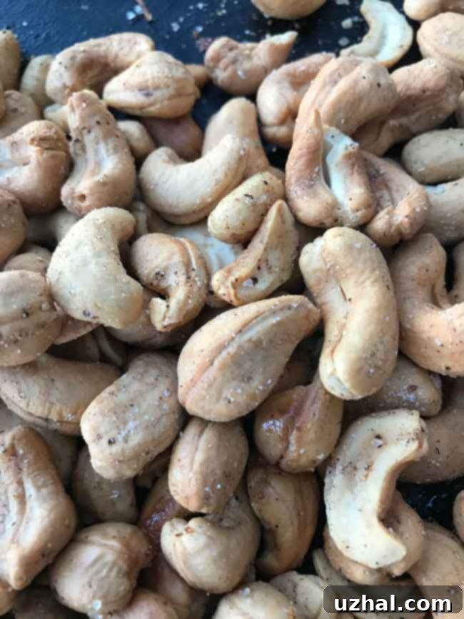 A close-up shot of perfectly roasted garlic cashews, showcasing their golden-brown color and visible savory spice coating, ready to be enjoyed as a snack.