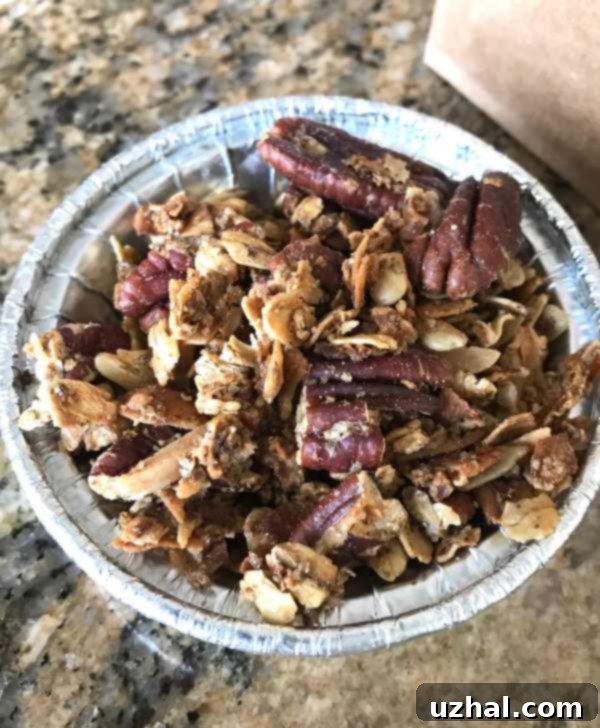 Flax Pecan Granola - A close-up of golden brown granola with visible pecans and oats on a baking sheet.