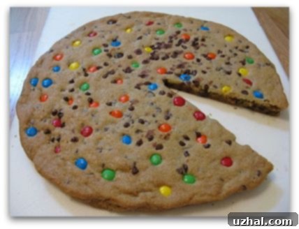 A baked M&M's chocolate chip cookie cake, golden brown and topped with candies, ready for frosting.