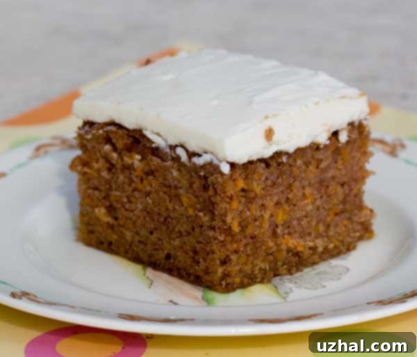 A perfectly baked slice of carrot cake with cream cheese frosting, showcasing its moist texture and rich color.