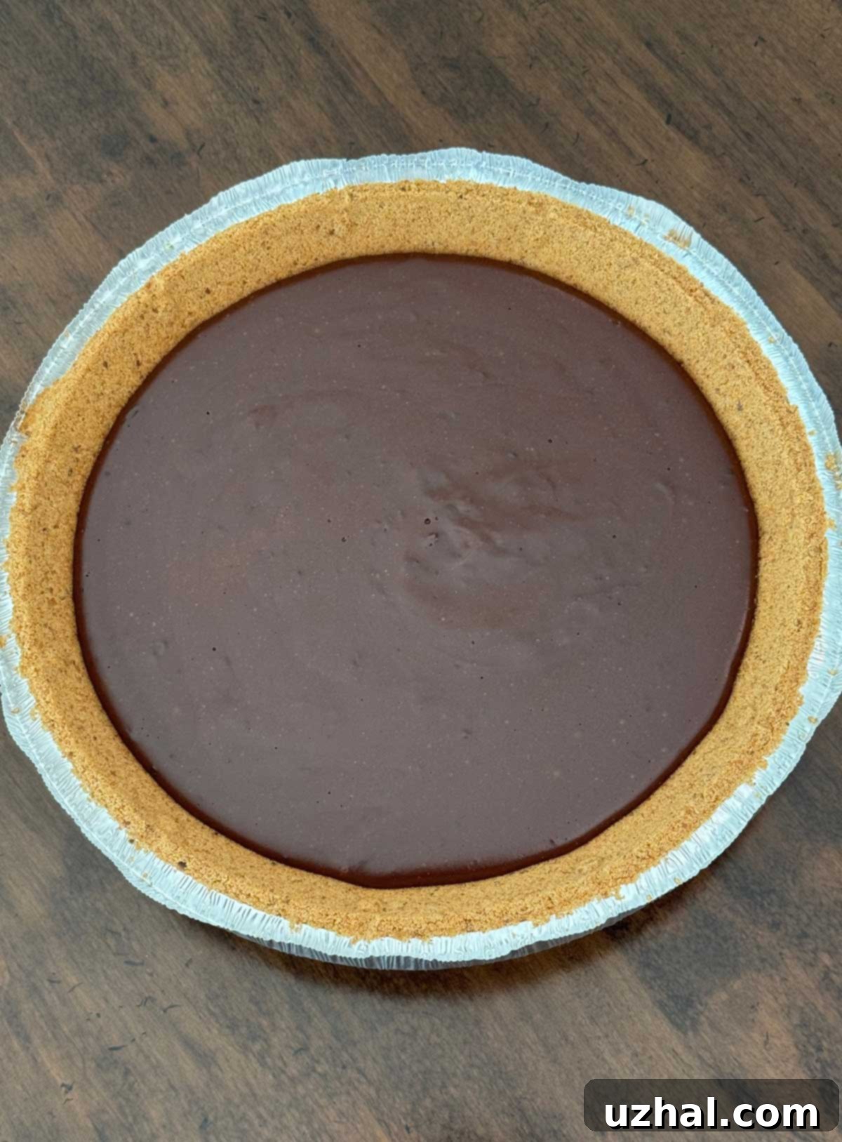 Evaporated milk chocolate pie filling scooped into a store-bought graham cracker crust, before adding whipped cream.