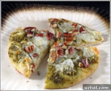 Delicious Pecan Pesto Pizza with melted cheese and toasted pecans, ready to serve on a cutting board.