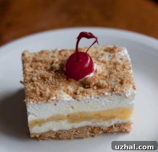 A vibrant slice of homemade Banana Split Cake, showcasing its distinct creamy layers and fresh fruit garnishes.