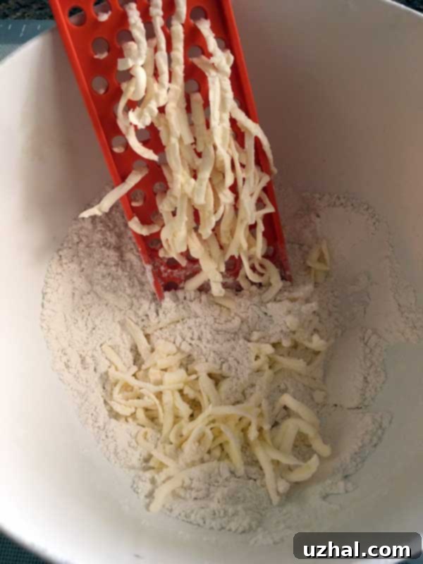 Shredding cold butter for pastry crust using a grater, illustrating the easy method.