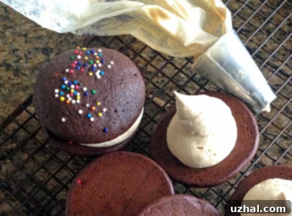 Peanut Butter Whoopie Pie filling being piped into a chocolate cookie half using a pastry bag