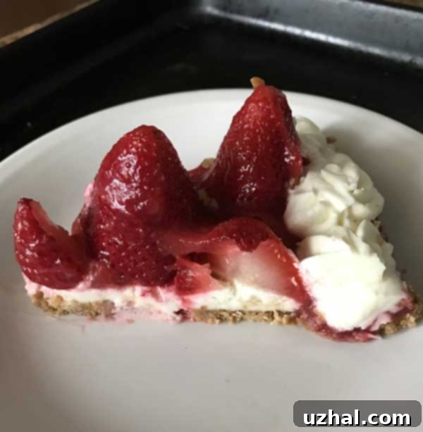 Sliced Strawberry-Almond Cream Tart on a white plate, showcasing fresh strawberries, creamy filling, and a golden graham cracker crust. Perfect for a refreshing dessert.