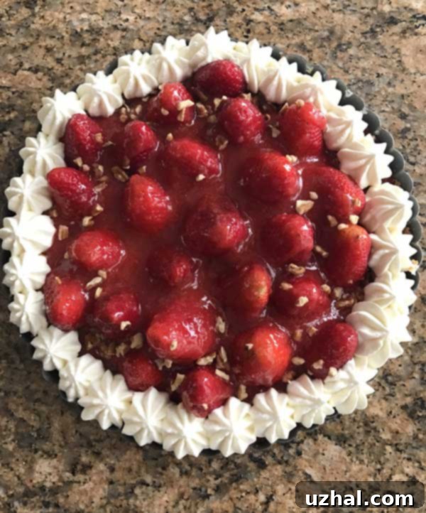 Top-down view of a Strawberry-Almond Cream Tart with pecans sprinkled around the edge, waiting to be served and enjoyed as a light dessert.