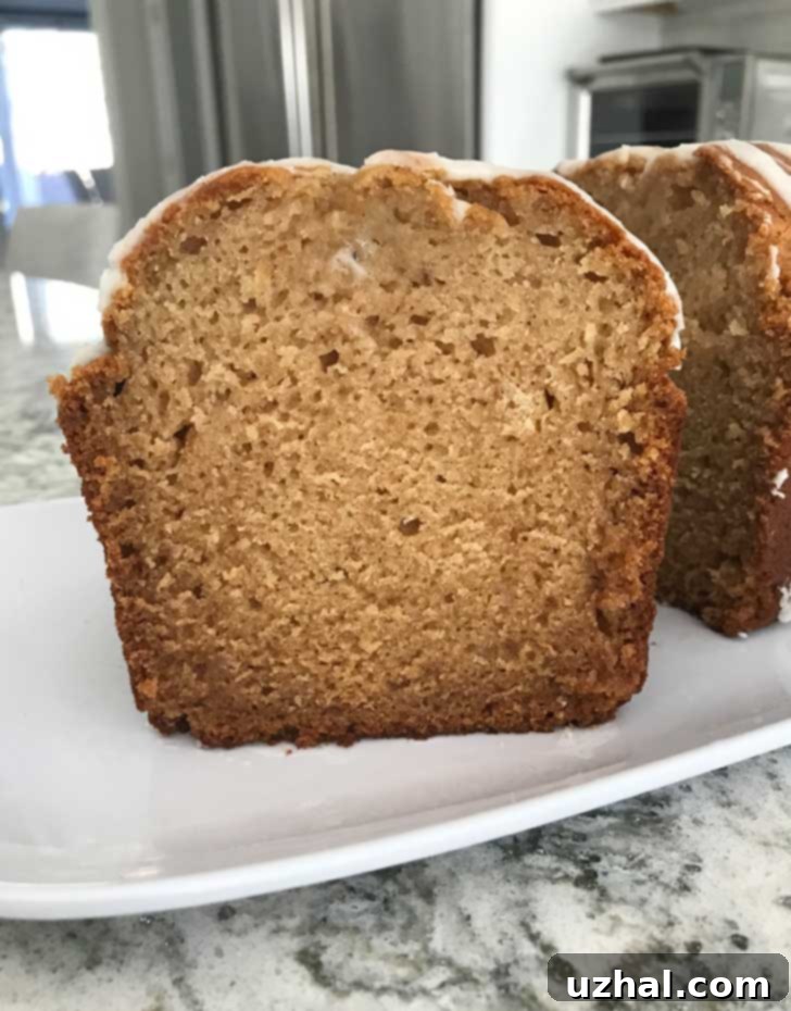 Freshly baked cardamom apple bread loaf, sliced in half, revealing a moist and spiced interior.