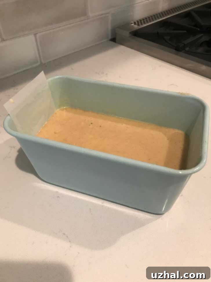 Apple bread batter fills a high-sided Jamie Oliver loaf pan about halfway, showing its readiness for baking.