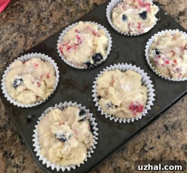 Freshly baked Blackberry Yogurt Muffins, golden brown with beautifully burst berries on top.