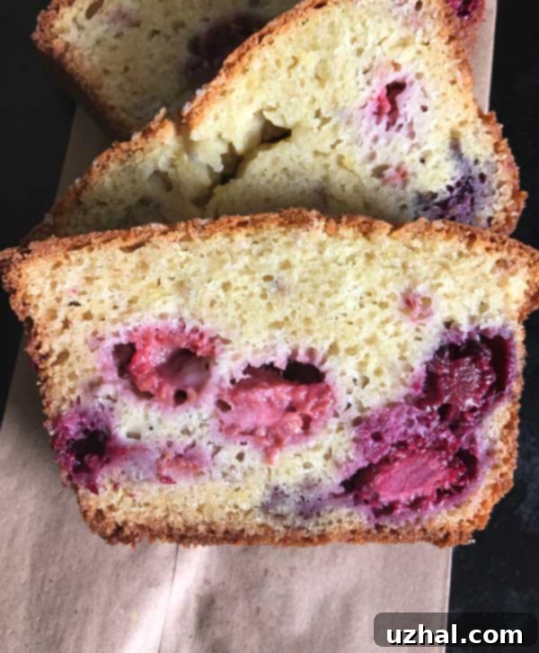 A close-up of a sliced Blackberry Yogurt Loaf, revealing its moist crumb and abundant, evenly distributed berries.