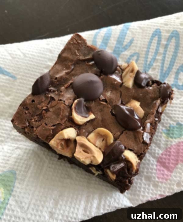 A stack of perfectly cut hazelnut brownies, showing their dense, fudge-like interior and a hint of the shiny, crackled top crust.