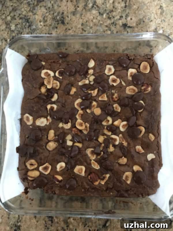 An overhead shot of an 8x8 inch baking pan filled with golden-brown hazelnut brownies, freshly baked and ready to be cooled.