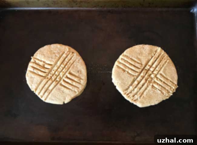 A baker pressing a large ball of peanut butter cookie dough with a sugared pie plate.