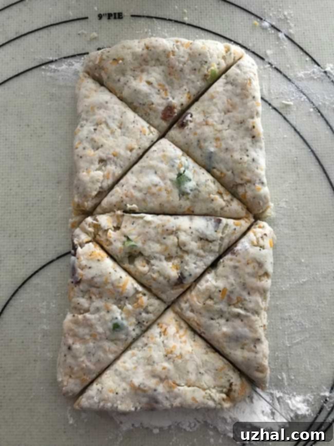 Unbaked Mini Bacon Cheddar Scones dough triangles on a parchment-lined baking sheet, ready for the freezer