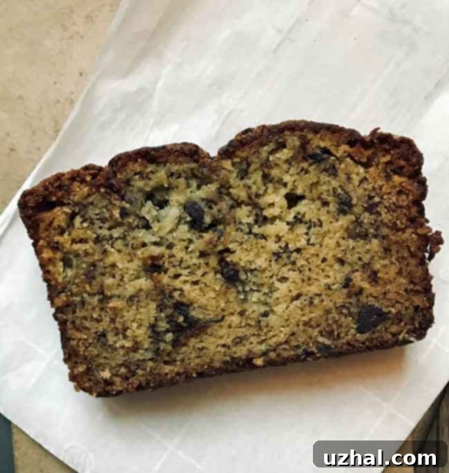 Close-up of a slice of Chrissy Teigen inspired banana bread, showing its dense texture and chocolate pieces