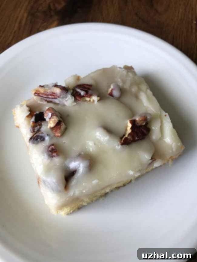 Delicious White Texas Sheet Cake topped with a smooth almond frosting and chopped pecans, served in a classic sheet pan.