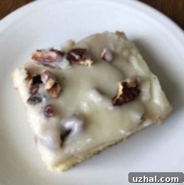 Slice of moist White Texas Sheet Cake with almond frosting on a white plate, ready to be enjoyed.