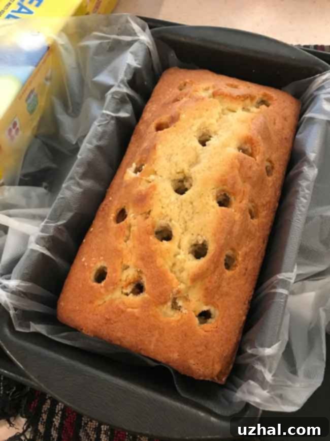 Pound cake with uniformly poked holes, meticulously prepared to absorb the strawberry Jell-O mixture.