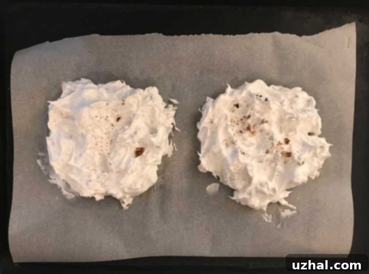 Raw meringue mixture with pecans spread into 6-inch circles on parchment paper, ready for baking