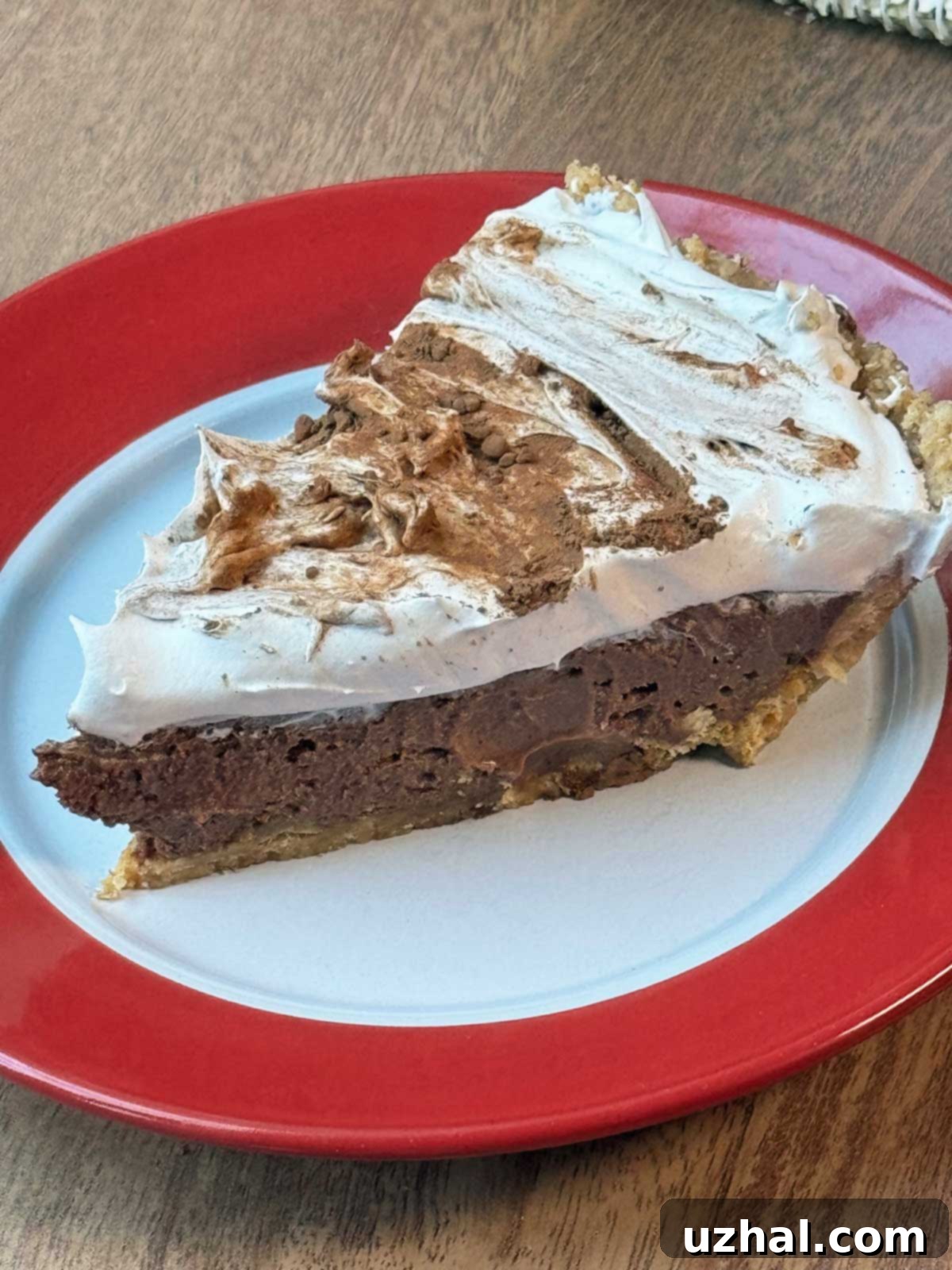 A beautifully sliced Mayan Chocolate Pie in a golden pastry crust, topped with a generous swirl of whipped cream and a sprinkle of cinnamon, showcasing its rich, creamy texture.