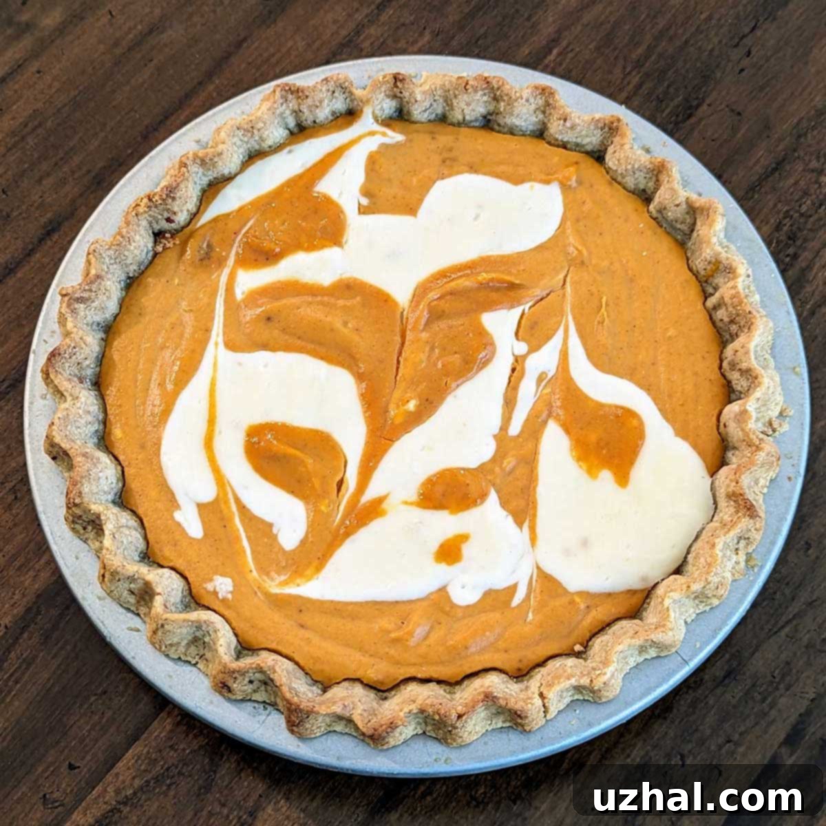 Marbled Cream Cheese Pumpkin Pie showcasing a perfectly smooth surface after baking in a metal dish, indicating optimal baking conditions.