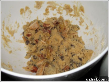 Pecan pie pieces being gently mashed into chocolate chip cookie dough