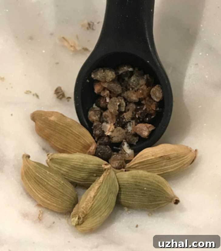 Close-up of whole green cardamom pods alongside a small pile of extracted cardamom seeds, highlighting their vibrant color and texture.