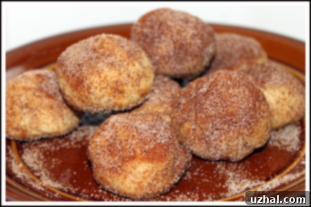A beautiful pile of Pan de Polvo cookies generously coated in cinnamon sugar, ready for serving on a white plate.