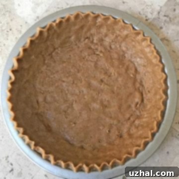 Unbaked pie shell with graham cracker flavored dough, ready to bake.