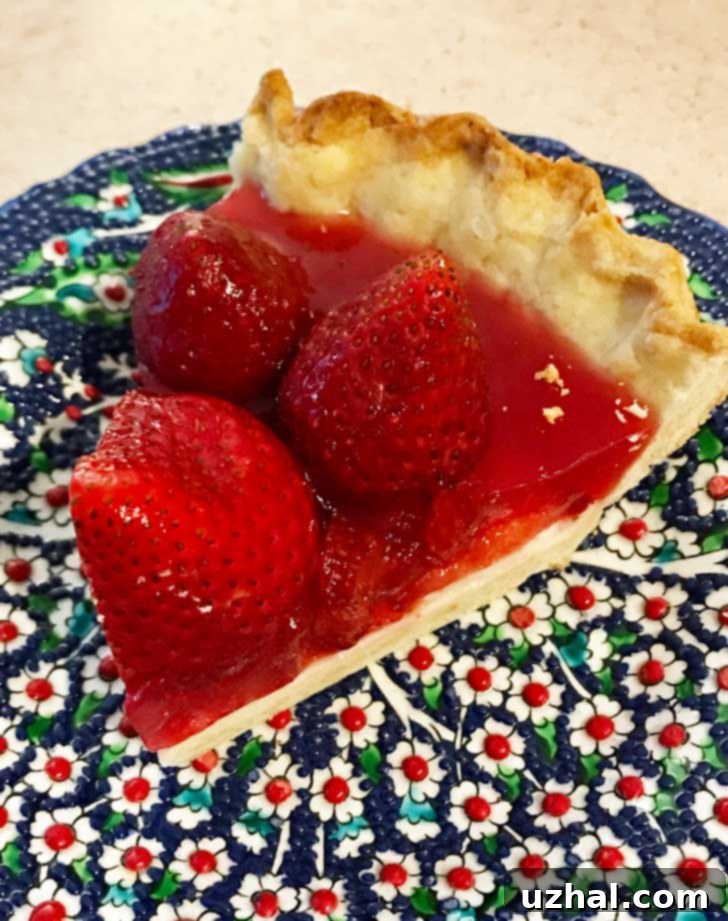 A slice of homemade glazed strawberry pie with cream cheese filling, nestled on a plate, highlighting the delicious gluten-free pastry crust.