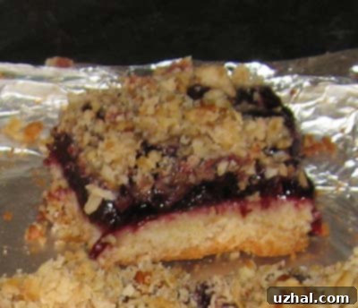 A close-up of a freshly baked Cherry Pie Bar, showing the crumb topping and cherry filling.
